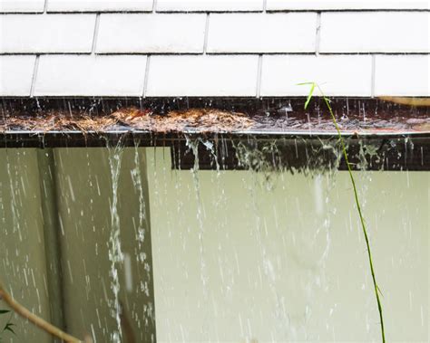 Gouttière bouchée et débordante d'eau sur le mur d'une maison