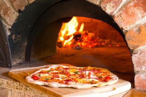 Pizza sortant d'un four à pizza au feu de bois