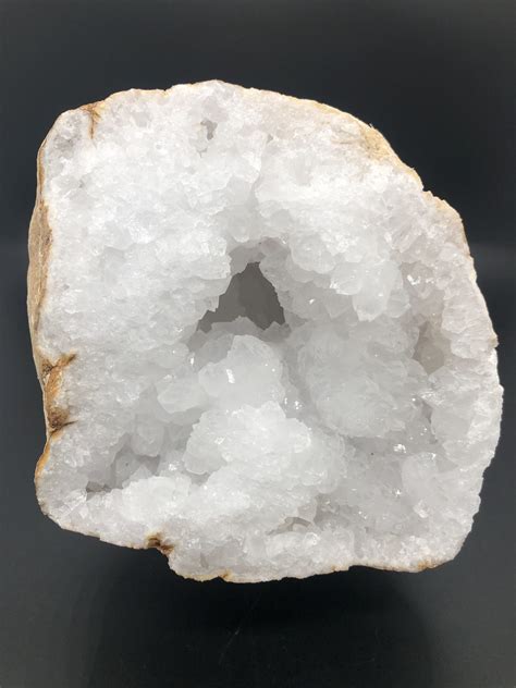 Une géode de cristal de roche avec une pierre de lune posée à côté