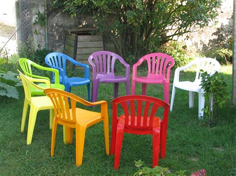 Enfants jouant dans un jardin avec des chaises en plastique multicolores