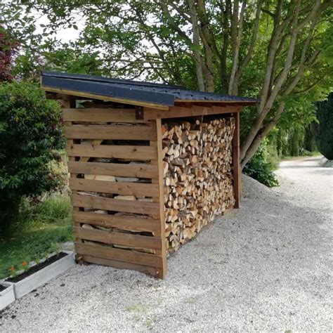 Abri à bois bien ventilé avec des bûches stockées sur palettes