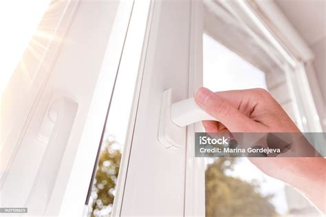 Personne ouvrant une fenêtre pour aérer une pièce