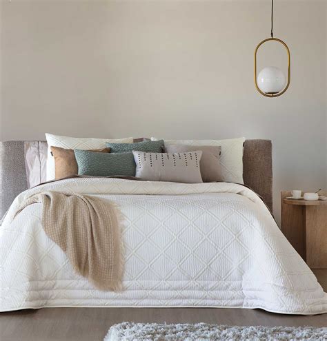 Un lit décoré avec un couvre-lit et un plaid joliment plié à ses pieds