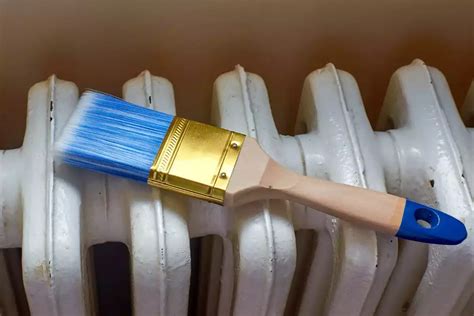 Pinceau appliquant de la peinture marron sur un radiateur